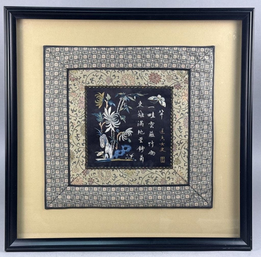 A Framed Chinese Silk Embroidery Panel: This Chinese silk embroidery panel features a central square of dark silk ground with polychrome silk thread embroidery. The central scene depicts a flowering chrysanthemum, a scholar's rock, and a bu