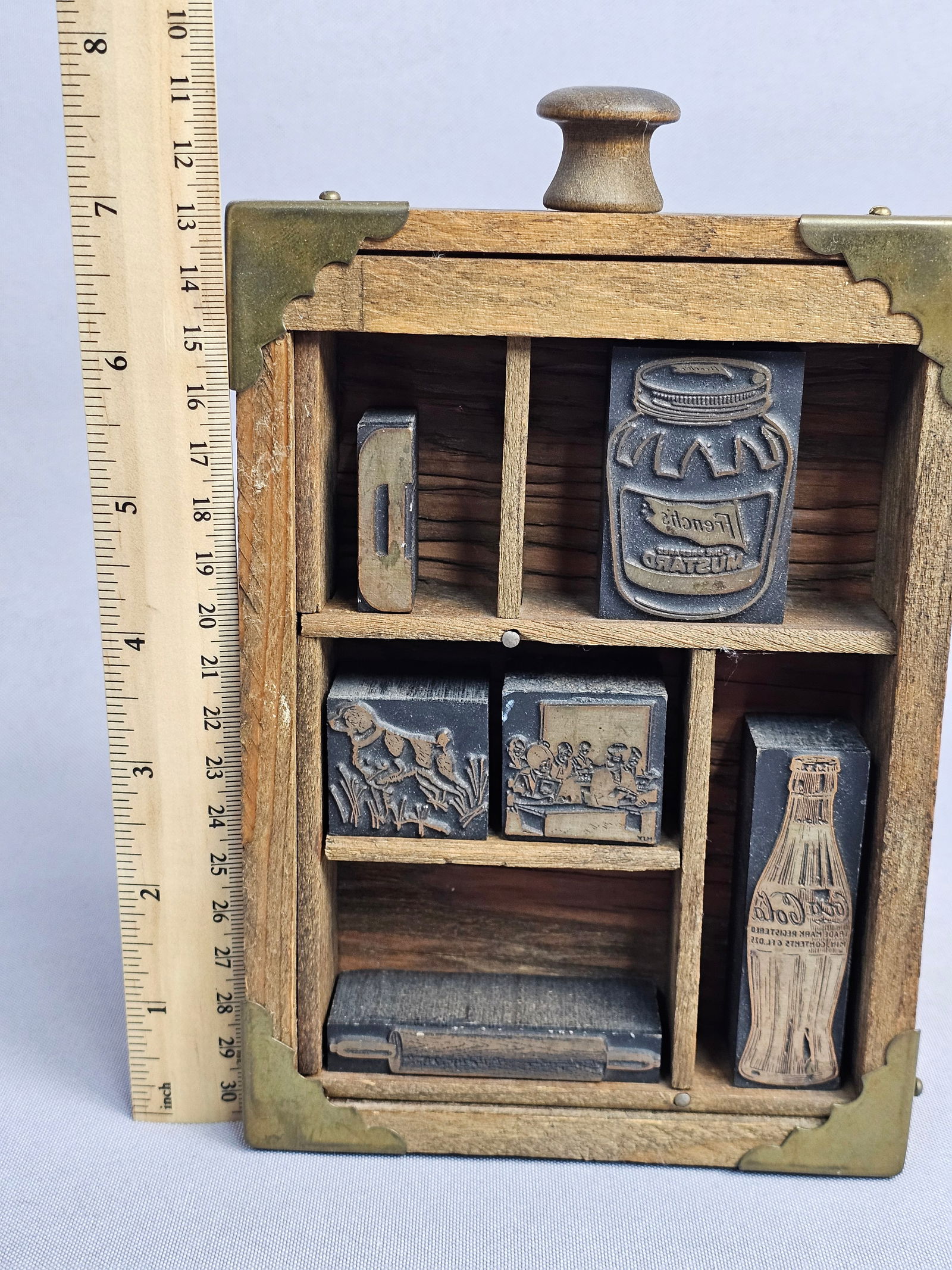 Vintage Wood-Mounted Metal Letterpress Printing Blocks in a Divided Display Case: An assortment of wood-mounted metal letterpress printing blocks featuring various advertising and pictorial subjects. The collection includes a Coca-Cola contour bottle, a French's Mustard jar, a roll
