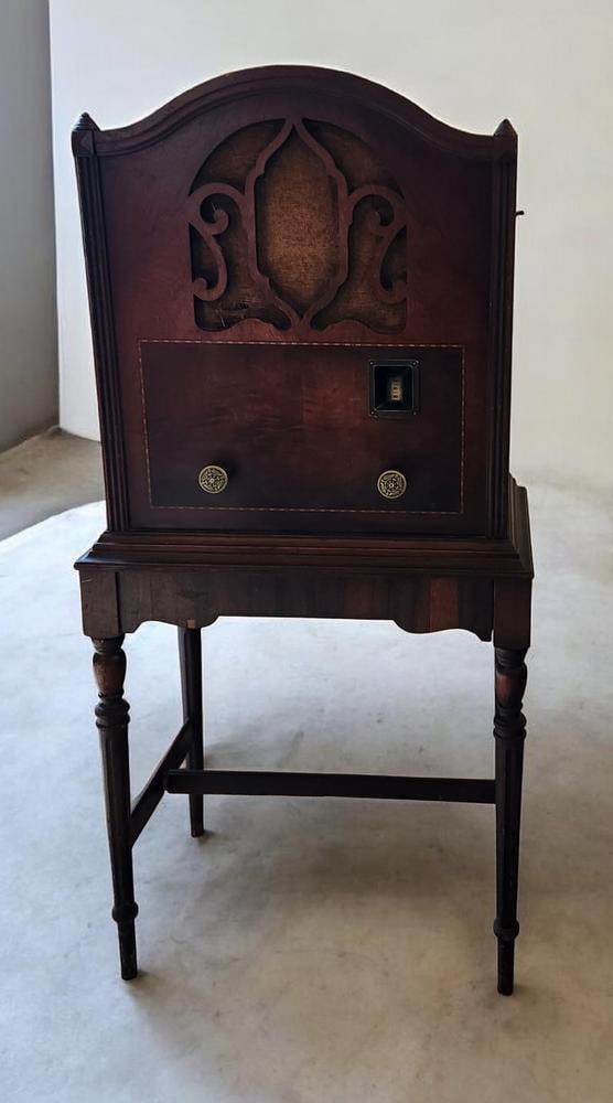 Antique Majestic Floor-Standing Tube Radio on Integrated Stand: An antique Majestic floor-standing tube radio dating from the late 1920s to early 1930s. The arched wooden cabinet features decorative finials and an ornate fretwork speaker grille with an aged fabric