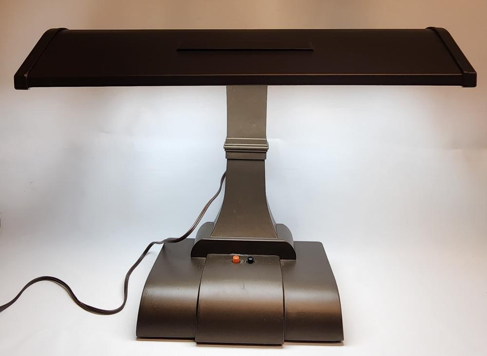 Mid-Century Modern Style Bronze-Tone Metal Desk Lamp: A mid-century modern style metal desk or piano lamp featuring a dark bronze-tone painted finish. The lamp is constructed with a long, rectangular shade supported by a single curved arm mounted to a ti