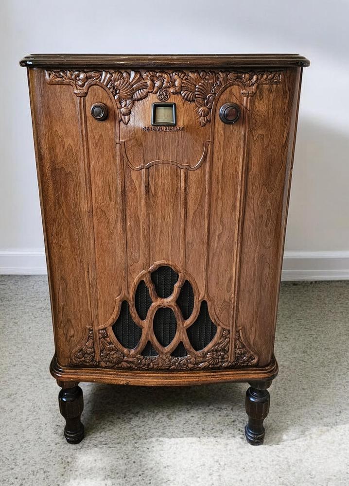 General Electric Model S-42A Console Radio: A General Electric Model S-42A console radio featuring an early 1930s Art Deco style wooden cabinet. The exterior construction includes ornate floral and shell carvings and four turned legs. Measures