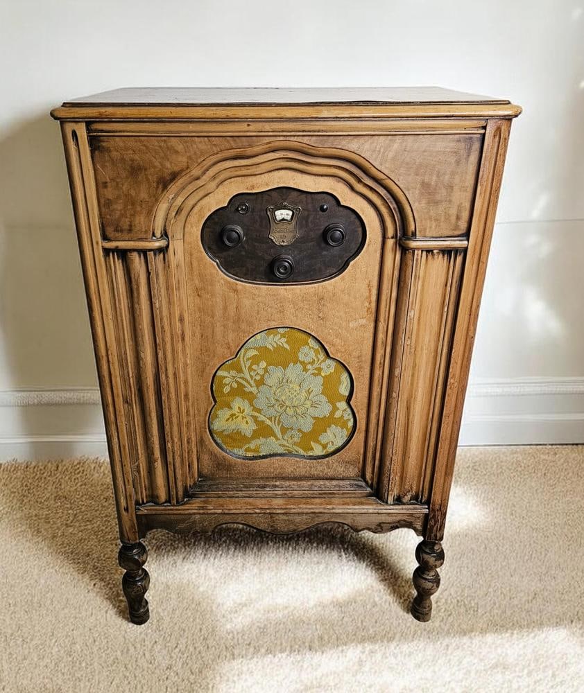 Atwater Kent Model 60 Console Radio: An Atwater Kent Model 60 console radio featuring a wooden lowboy-style cabinet with an arched front and turned spindle legs. The central control panel includes a brass-toned plate marked ATWATER KENT