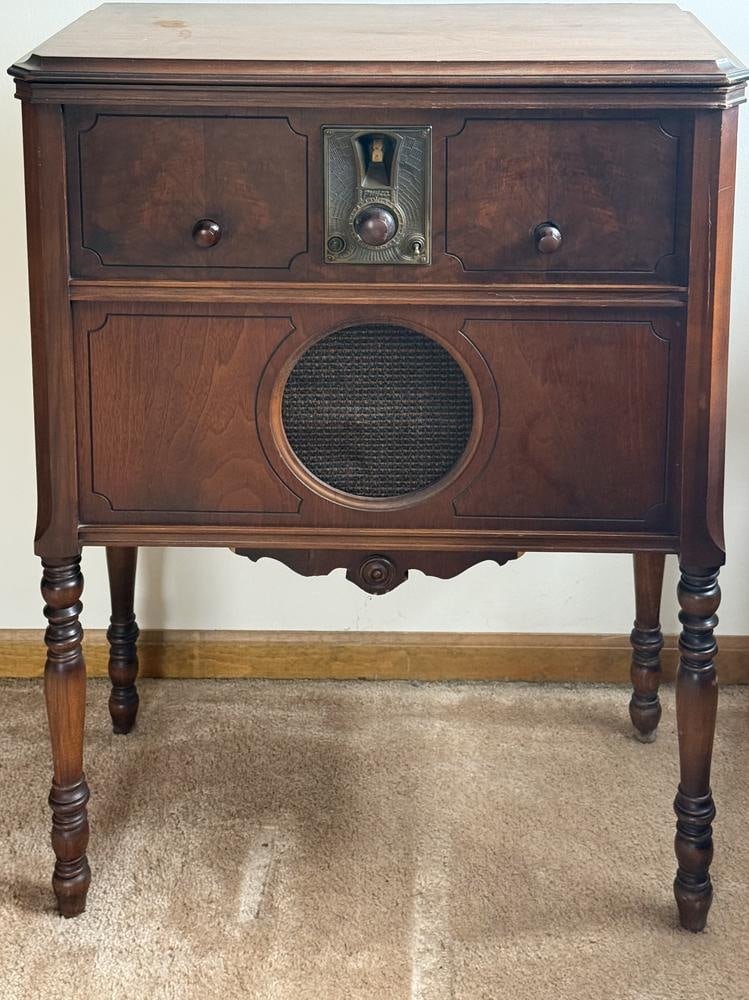 Philco Neutrodyne Plus Console Radio: This item is located on the second floor. This Philco Neutrodyne Plus console radio is housed in an Art Deco style wooden cabinet featuring turned legs and decorative paneling. The front of the unit i