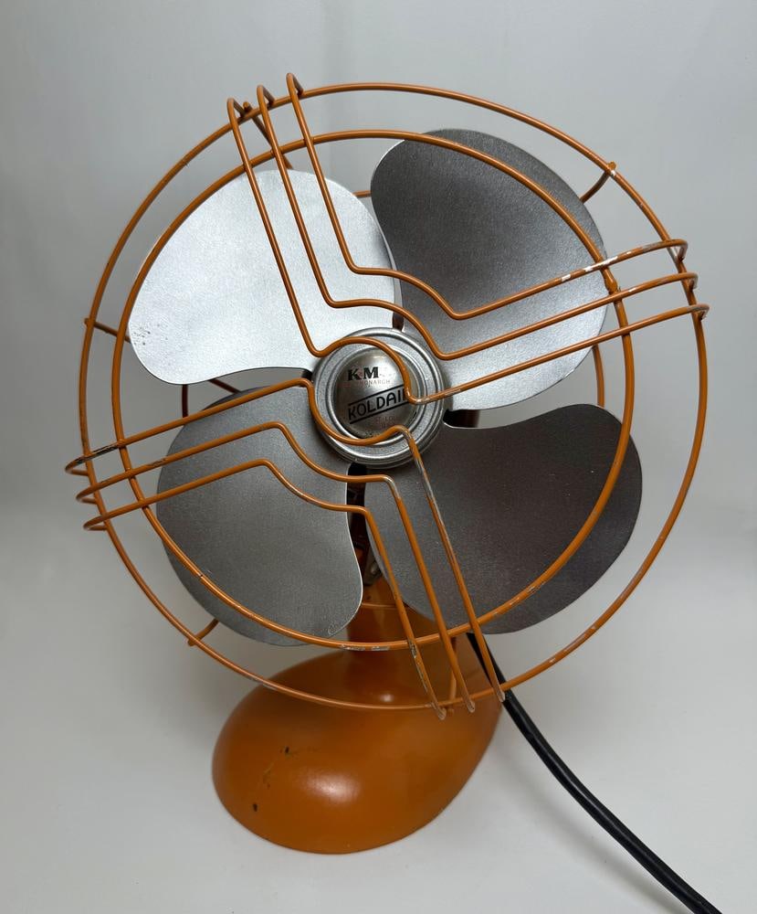 A Knapp-Monarch Koldair Electric Desk Fan: This item is located on the second floor. A mid-century electric desk fan manufactured by Knapp-Monarch in St. Louis, Missouri, under the Koldair brand name. The fan is constructed with an orange-pain