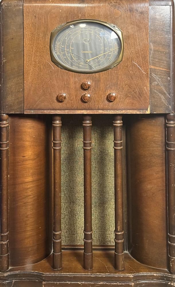 Coronado Art Deco Console Radio with Rola Speaker: This item is located in the basement. A Coronado console radio featuring a floor-standing wooden cabinet with Art Deco design elements. The cabinet is constructed with rounded side pillars and three