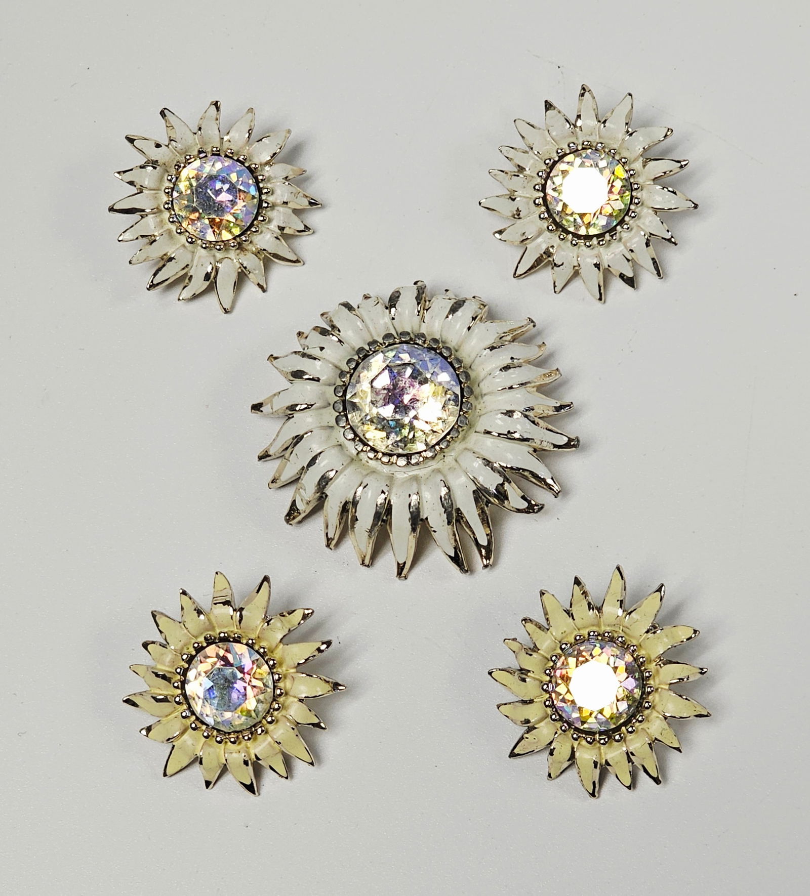 Weiss Enamel Rhinestone Sunflower Jewelry: This collection of vintage costume jewelry by Weiss features a sunflower-style brooch and matching clip-on earrings. Each piece is crafted from gold-toned metal with pointed petals finished in white