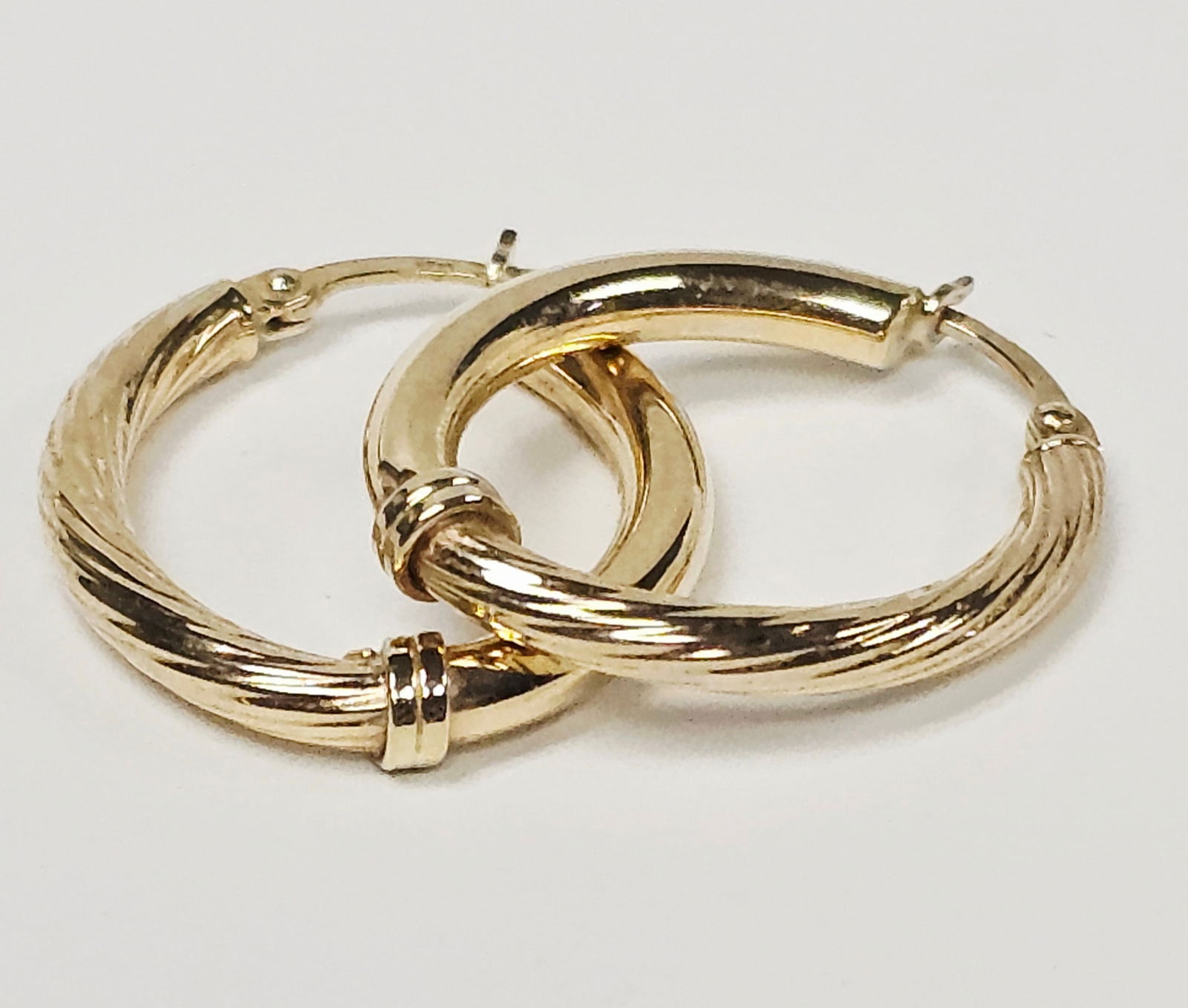 14K Yellow Gold Textured Hoop Earrings 3.1 Grams: A pair of 14K yellow gold hoop earrings featuring a combined smooth and textured ribbed design. Each earring is accented with a small decorative band at the base and is equipped with a hinged ear