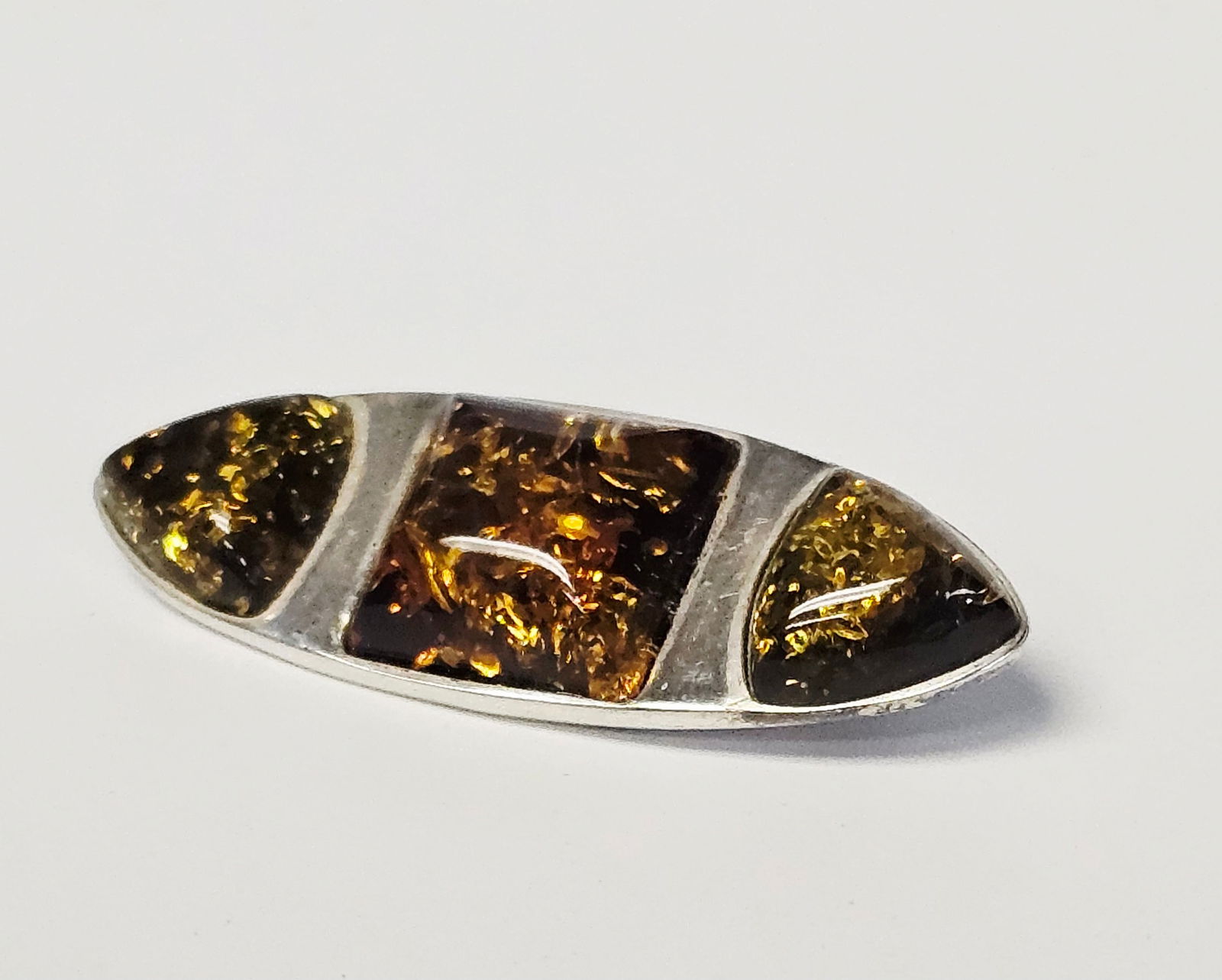 Baltic Amber and Sterling Silver Brooch 3.9 Grams: This modernist-style brooch is crafted from sterling silver and features three bezel-set Baltic amber cabochons. The design consists of a central square cabochon flanked by two triangular cabochons,