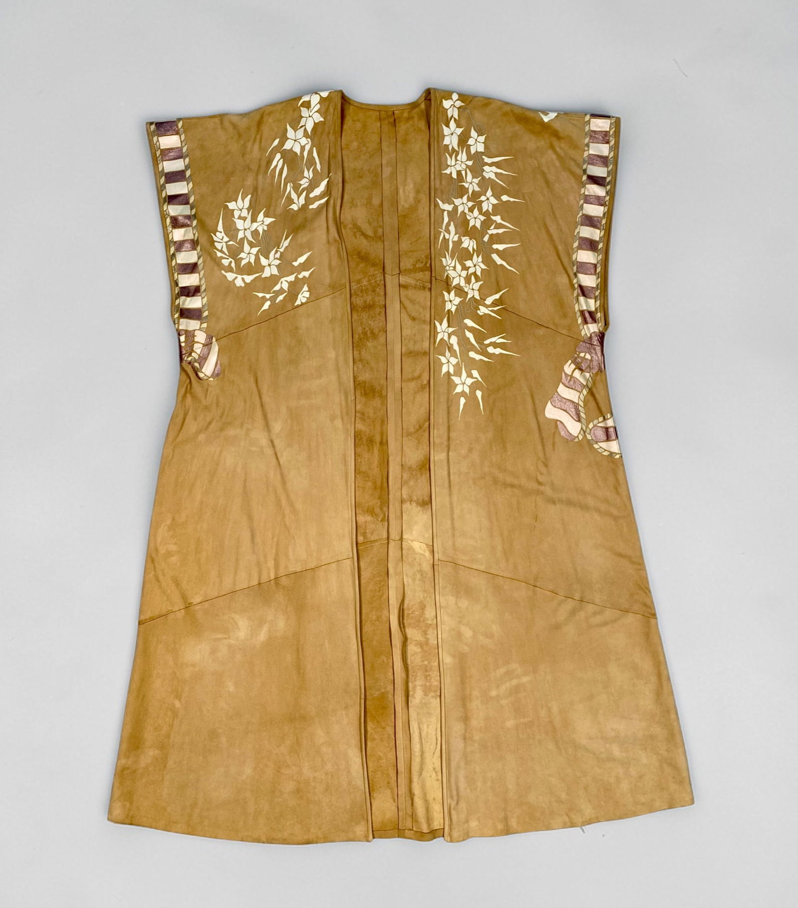 A Contemporary Hand-Painted and Appliqu?©d Suede Duster: This contemporary sleeveless, open-front duster is crafted from tan-colored suede. The garment features elaborate hand-painted and appliquéd artistic designs. The front is decorated with white