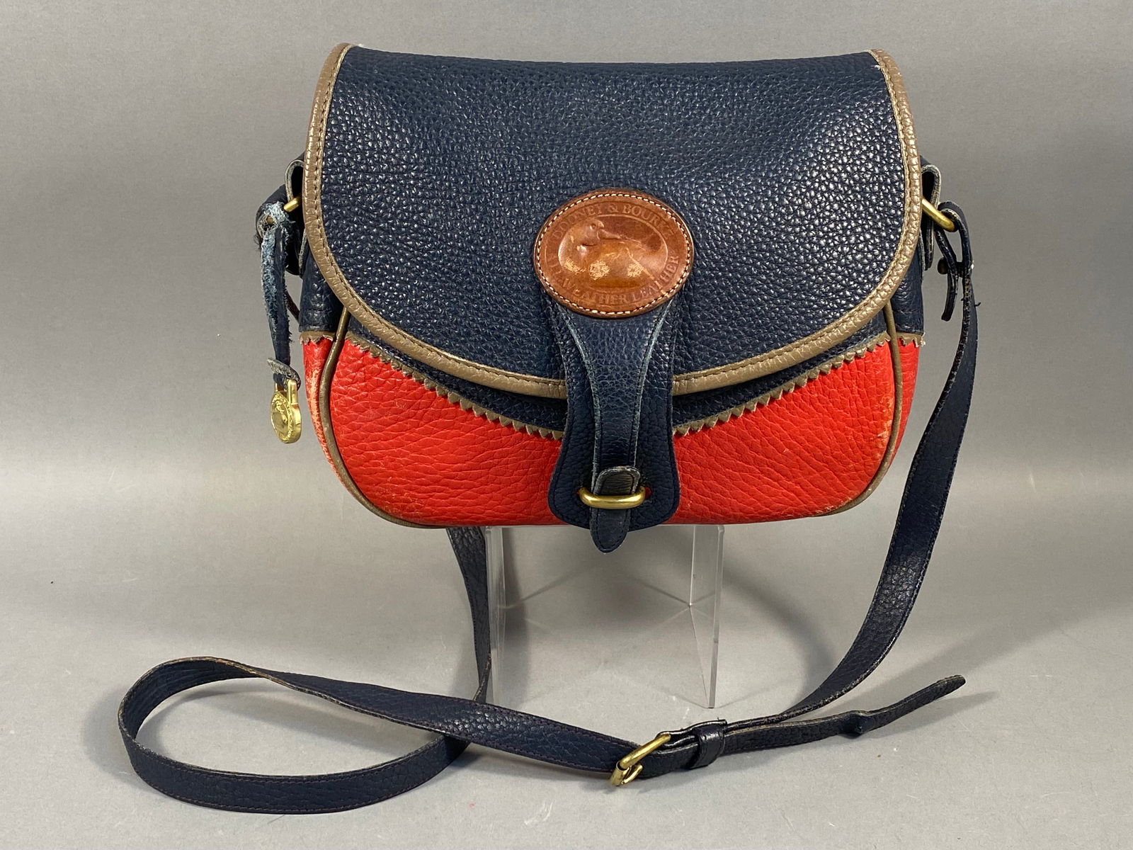 Dooney & Bourke All-Weather Leather Teton Shoulder Bag: A vintage Dooney & Bourke Teton shoulder bag crafted from signature All-Weather Leather featuring a pebbled texture and smooth leather trim. This two-tone color block design presents a navy blue f