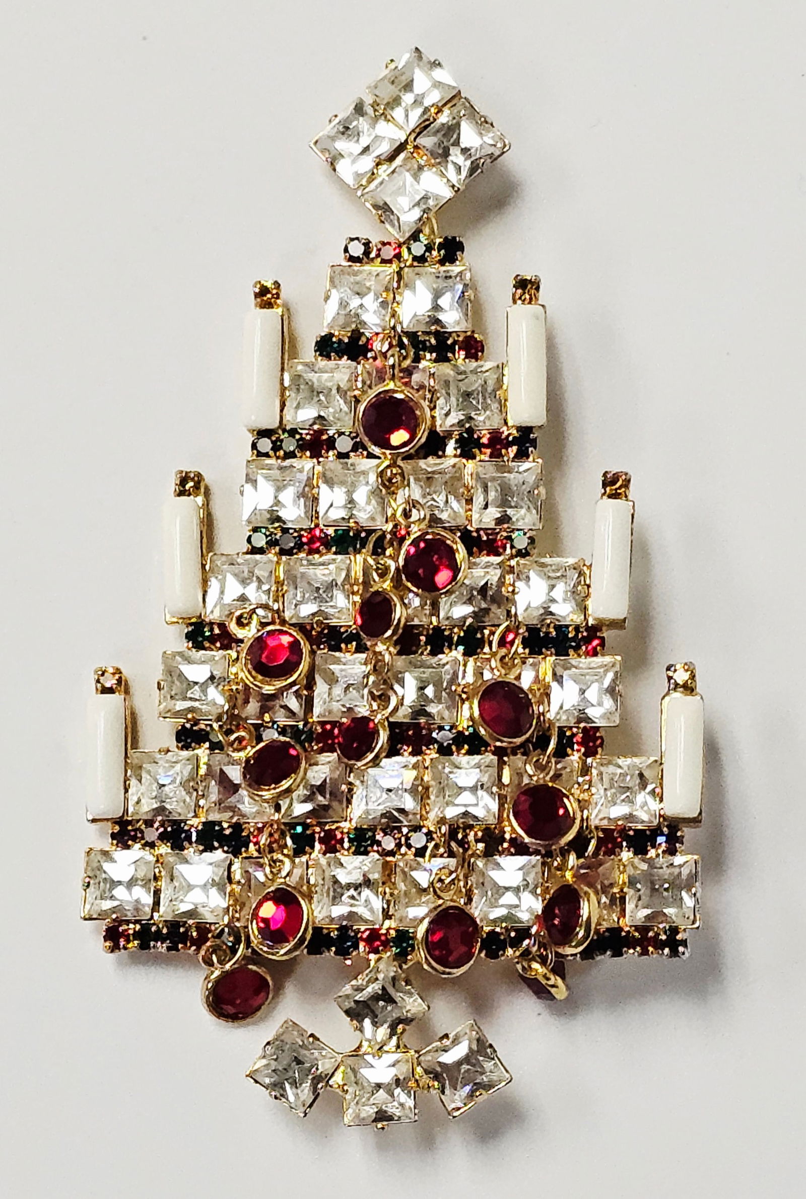 Vasari Rhinestone and Crystal Christmas Tree Brooch: A vintage tiered Christmas tree brooch by Vasari, crafted in yellow gold-tone base metal. The architectural design features multiple rows of prong-set, square-cut clear crystals and a matching star to