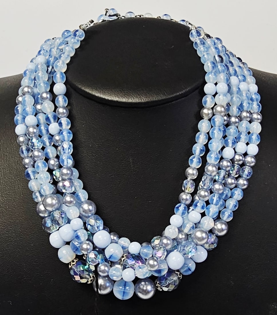 Coro Five-Strand Beaded Bib Necklace Hang Tag: A vintage mid-20th century multi-strand bib necklace by Coro. The piece is constructed with five graduated strands of various costume beads in a tonal blue and lavender palette. The composition includ