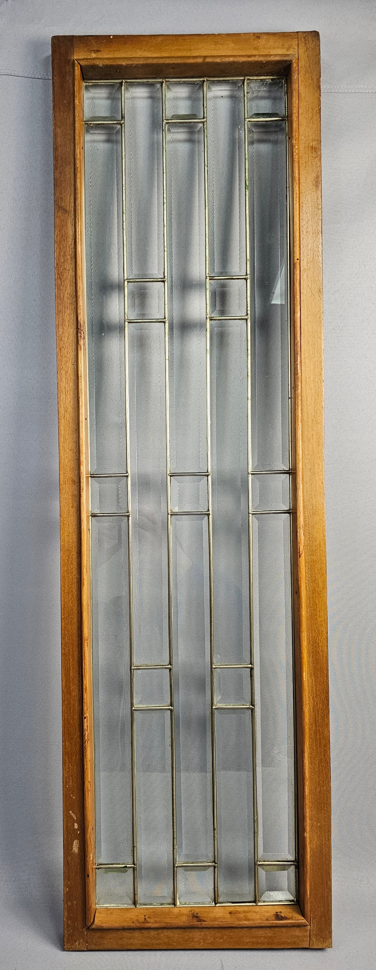 Vintage Leaded and Beveled Glass Architectural Panel: An architectural panel featuring clear beveled glass panes arranged in a linear geometric pattern. The panel is housed in a dark-stained wooden frame which includes an integrated keyhole. The construc