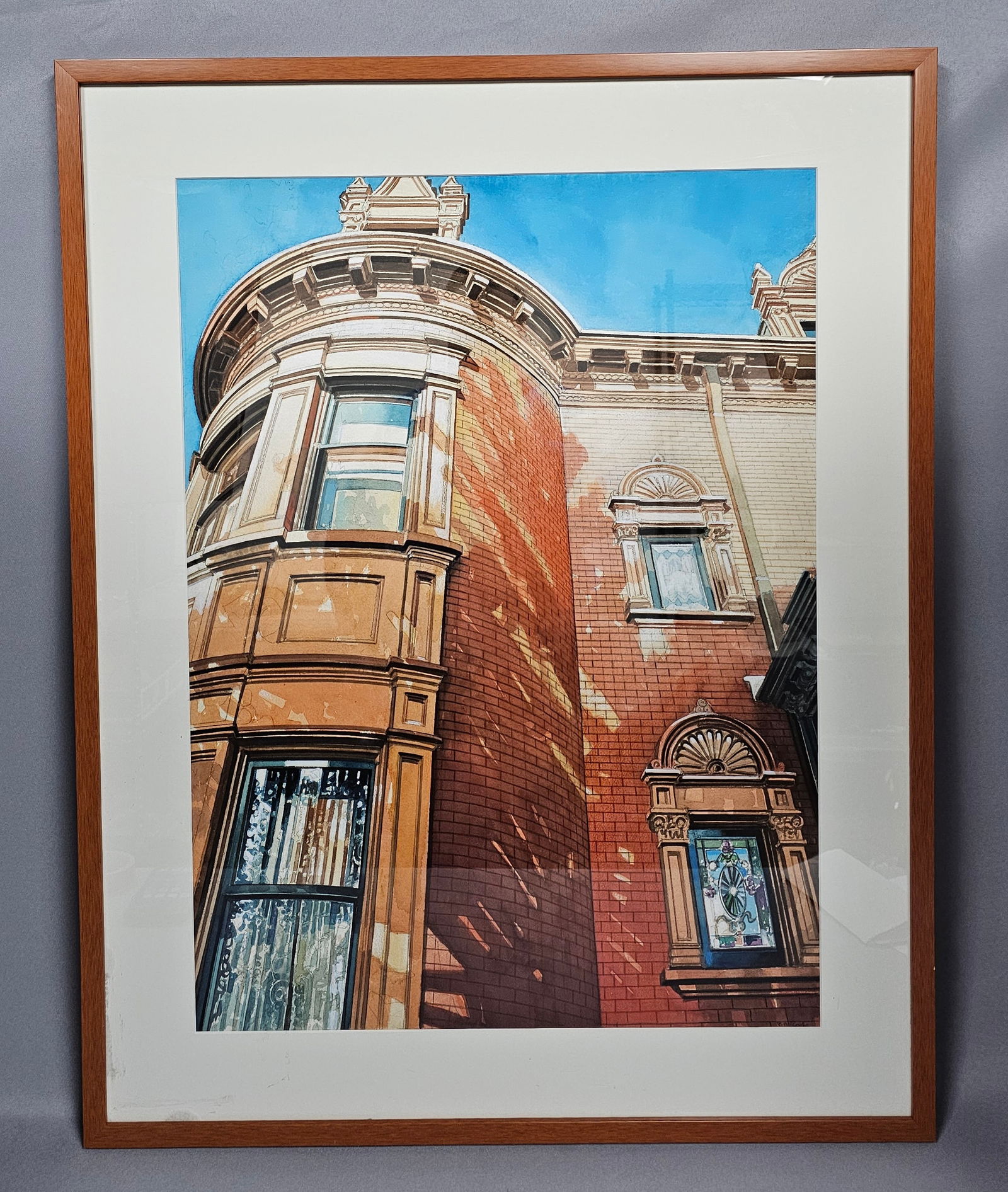 Signed Bruce McCombs Original Watercolor of the Voigt House: A framed watercolor by Bruce McCombs depicting architectural details of the Voigt House in brick-red and tan tones. Measures approximately 29 by 36.5 inches tall Left lower white mat has