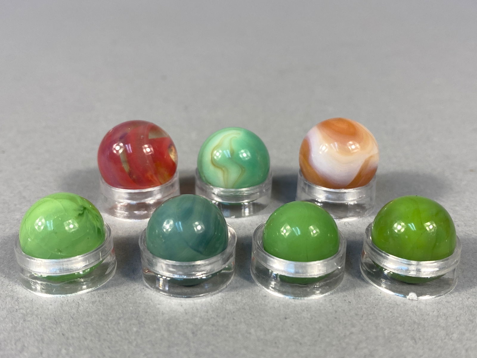 Various American Manufacturers, Collection of Seven Vintage Glass Marbles, Swirl and Opaque: This lot consists of a curated collection of seven vintage glass marbles, representing various styles and manufacturing techniques common in the mid-20th century. The assortment includes a striking re