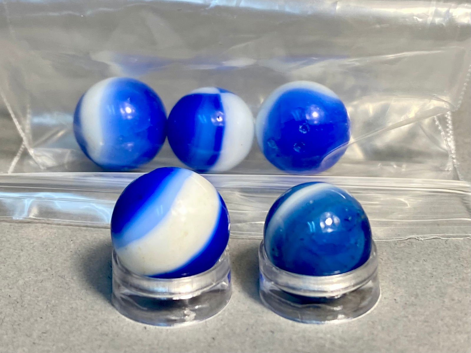 Marble King Vintage Rainbow Marbles Cobalt Blue and White Patch Mid-20th Century: This collection features five machine-made glass marbles attributed to the Marble King Rainbow series. Produced during the mid-20th century, these specimens showcase the manufacturer's classic swirlin