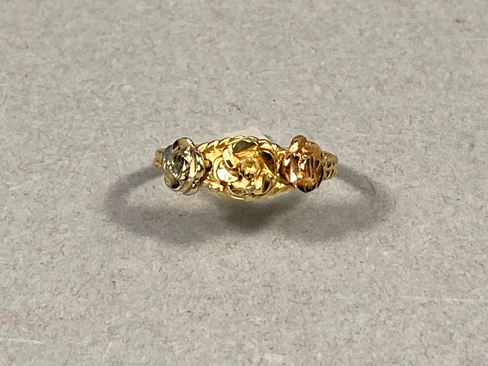 14 Karat Tricolor Gold Floral Rose Ring, 2.67g: This ring is crafted in 14 karat tricolor gold, featuring a central decorative element of three sculpted rose motifs in yellow, white, and rose gold tones. The floral cluster is mounted on a textured,