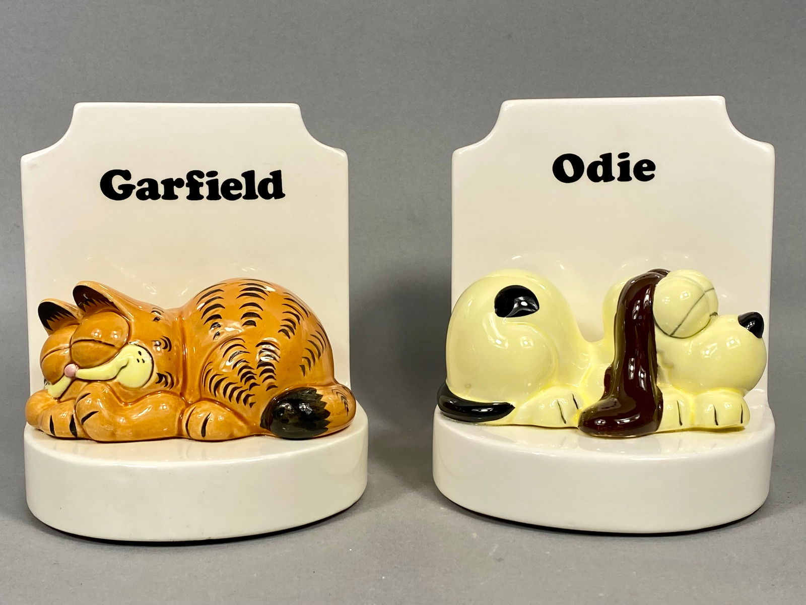 Enesco Glazed Ceramic A Pair of Garfield and Odie Bookends: A pair of licensed character bookends manufactured by Enesco, featuring Jim Davisâ€™s iconic comic strip characters Garfield and Odie. Each piece is constructed from slip-cast glazed ceramic w