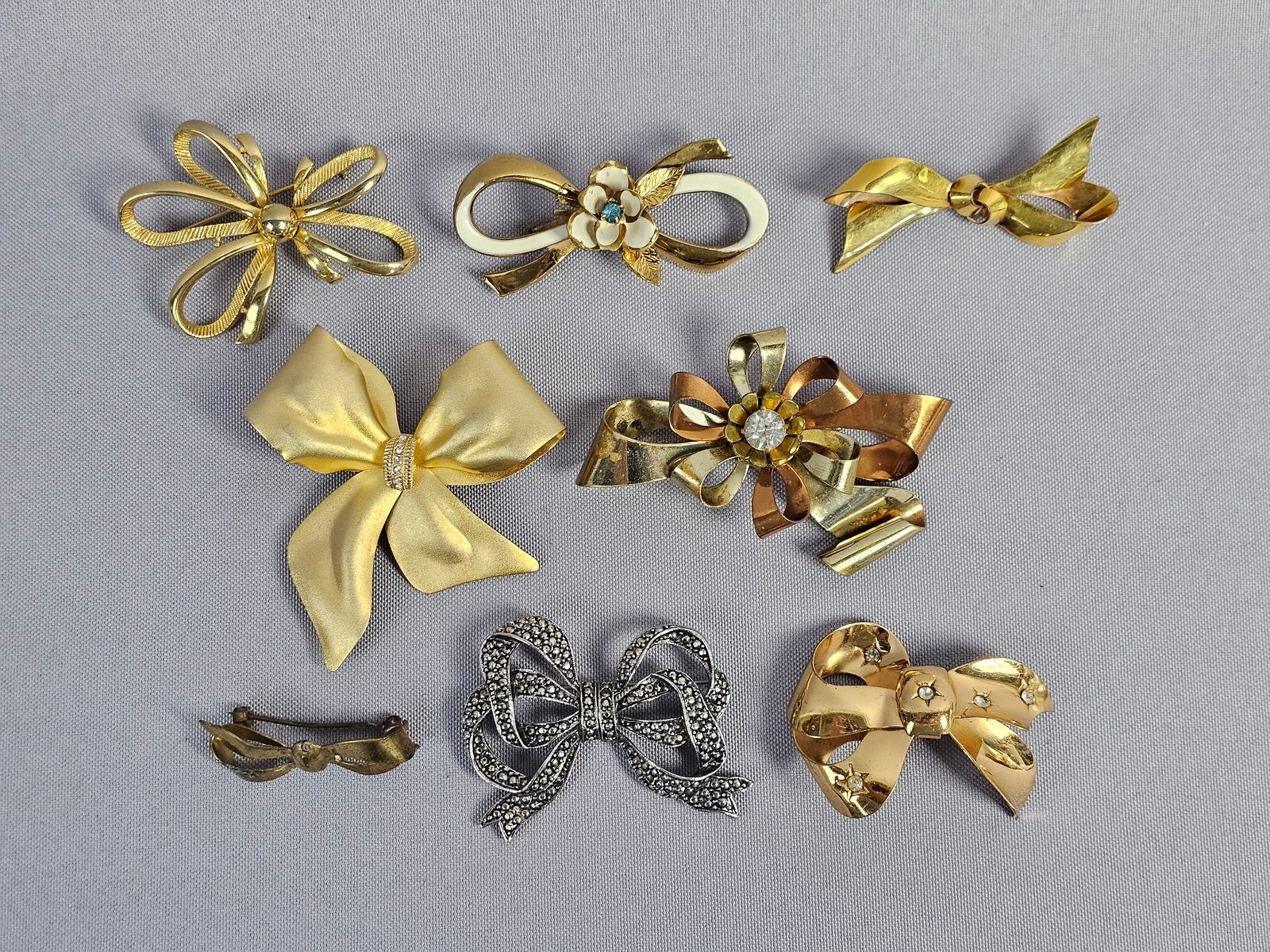Collection of Vintage Gold-Tone and Gold-Filled Bow Brooches including Coro: This collection features a variety of vintage bow and ribbon motif brooches in gold-tone, silver-tone, and gold-filled metals. The group includes a 1/20 12K gold-filled polished ribbon bow, stamped wi