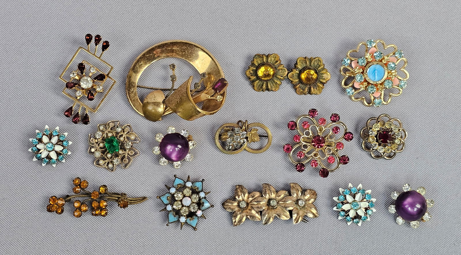 Gold-Tone and Sterling Silver Vintage Costume Jewelry Brooch and Pin Collection: A diverse collection of vintage jewelry pieces featuring a variety of mid-century motifs. The lot includes a standout gold-tone religious brooch with a central blue glass Madonna medallion, accented b