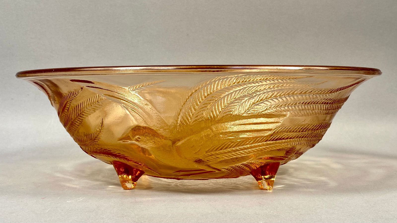 Tiara Exclusives, Pressed Amber Glass, Bird and Fern Footed Bowl: This large centerpiece bowl was produced for Tiara Exclusives, a prominent American glass distributor, with manufacturing attributed to the Indiana Glass Company. The piece is crafted in translucent a