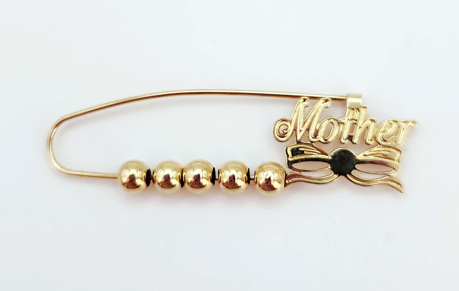 14K Gold Mother Pin Brooch 0.8 Grams: A 14K yellow gold sentimental brooch fashioned in the style of a safety pin. The decorative pin features several spherical gold beads threaded onto the lower bar and is accented at the clasp end with