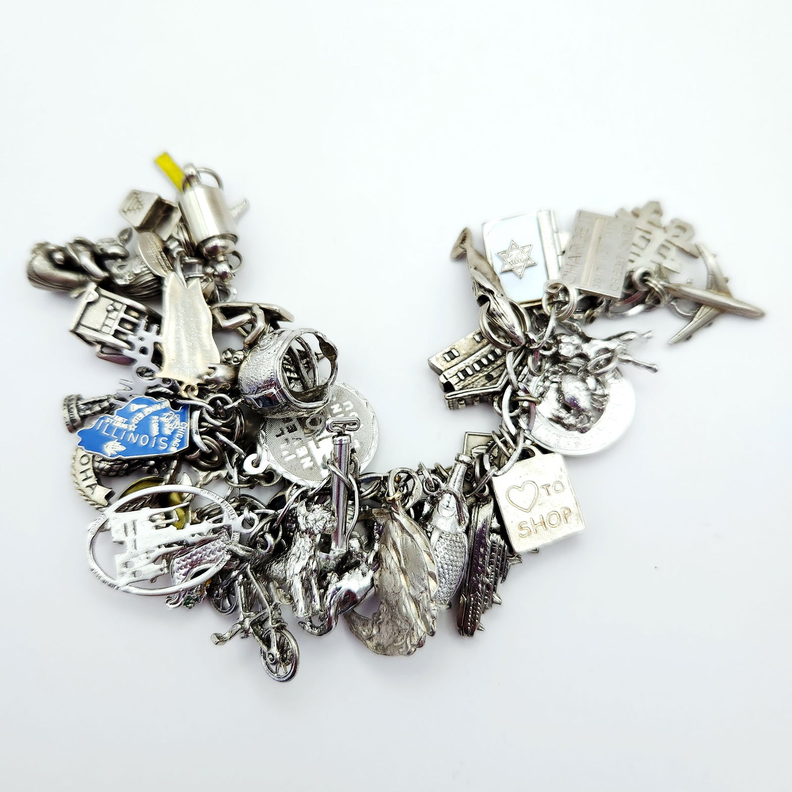 Sterling Silver Charm Bracelet 98.1 Grams: This lot features a vintage sterling silver charm bracelet heavily adorned with a collection of travel-related and novelty charms. The assembly includes various charms such as an airplane, a whale, a