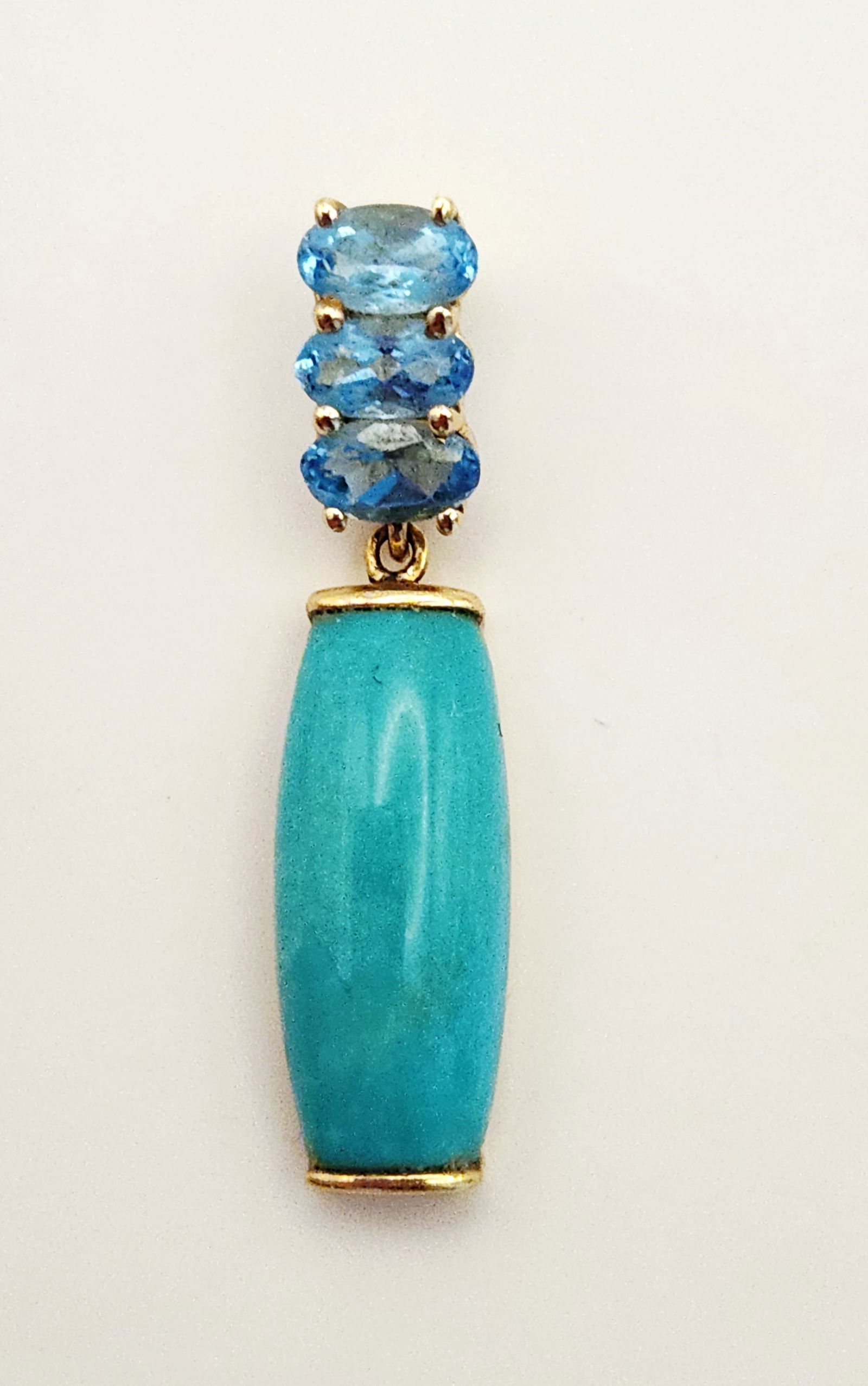 14K Gold Turquoise Pendant 1.6 Grams: This vertical drop pendant is crafted in 14K yellow gold. The upper portion features three vertically aligned, prong-set oval faceted light blue gemstones, which appear to be blue topaz or aquamarine.