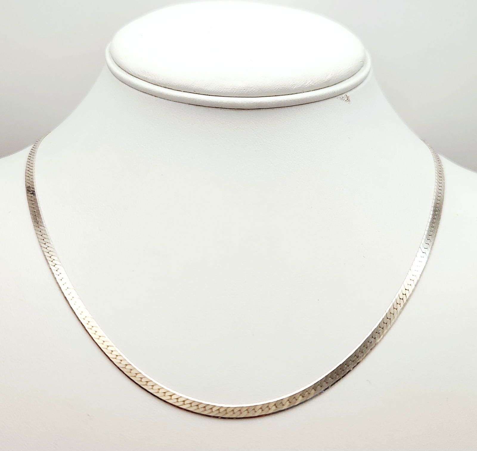 Sterling Herringbone Necklace 6.79 Grams: This sterling silver necklace is designed in a classic herringbone flat chain style. The piece features interlocking flat links and is secured by a spring ring clasp. The end cap is hallmarked with th