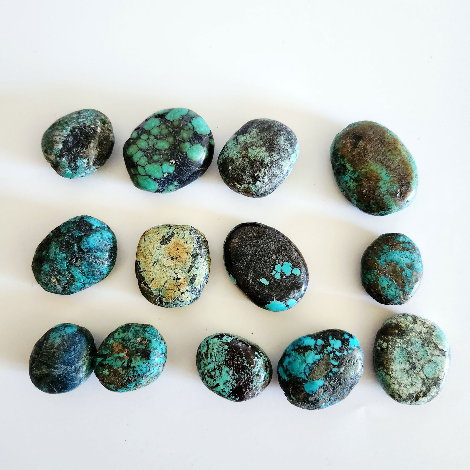 Collection of Polished Turquoise Stones: A collection of polished turquoise stones displaying various shades of blue and green with black and brown matrix patterns, ranging from approximately 1 to 2 inches in length. Good vintage condition.
