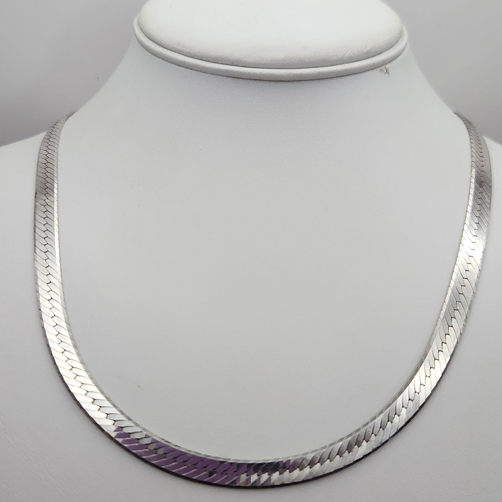 Sterling Flat Herringbone Necklace 25.3 Grams: This sterling silver necklace is designed in a flat herringbone style, featuring a flexible multi-link construction with a high-polish finish. The piece is secured with a lobster claw clasp and is mar