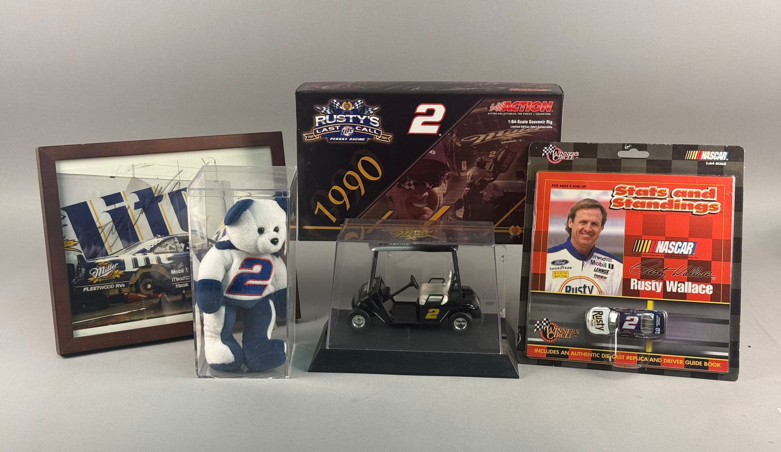 A Collection of Rusty Wallace NASCAR Memorabilia and Die-Cast Models: A collection of NASCAR memorabilia celebrating the career of driver Rusty Wallace, primarily featuring items from his tenure with the number 2 Miller Lite racing team. The group includes a framed colo