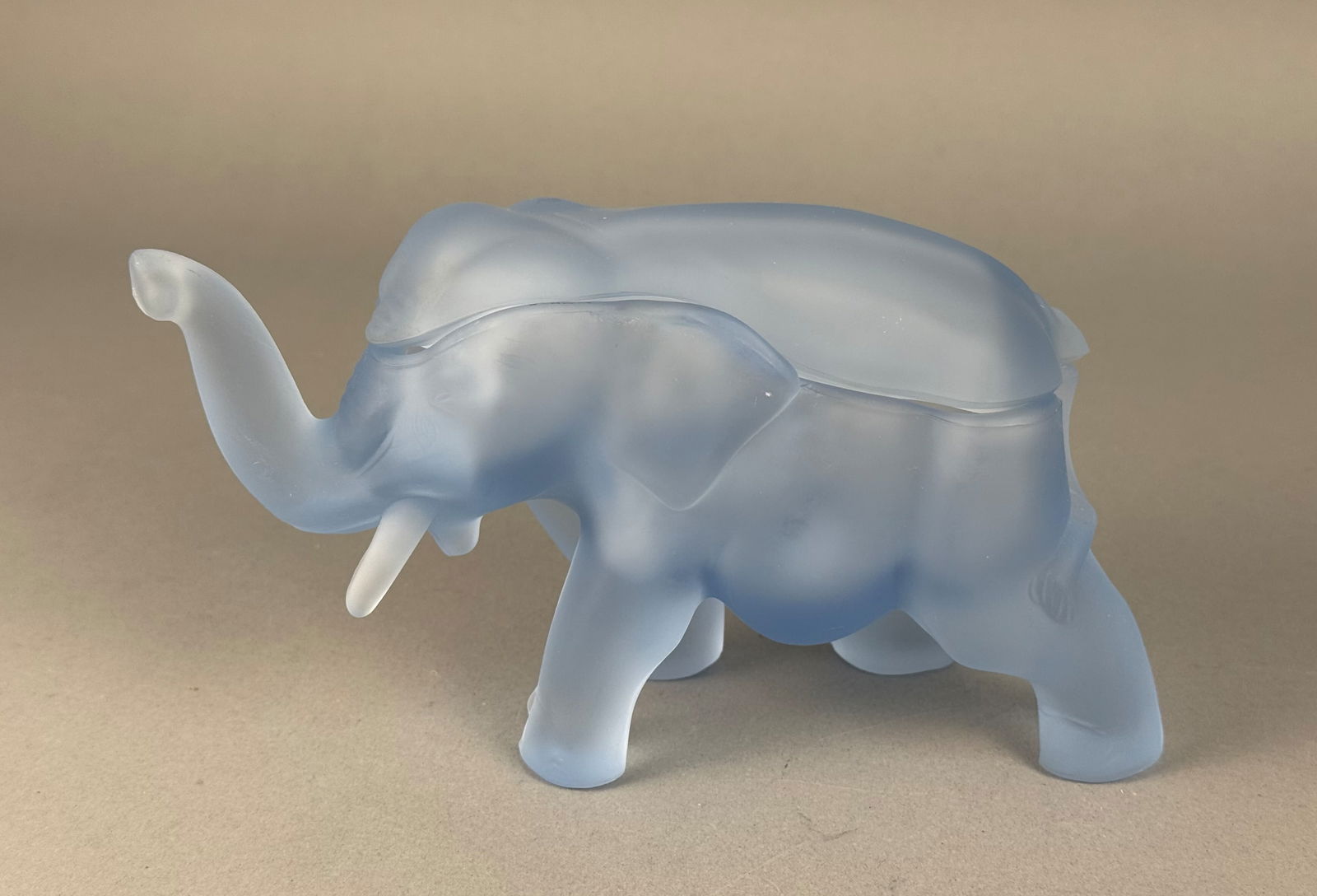 Tiara Exclusives Frosted Blue Satin Glass Elephant Covered Candy Dish: A Tiara Exclusives frosted blue satin glass covered candy dish in the form of an elephant. The two-piece construction consists of a hollowed base and a removable lid forming the elephant's back. The f