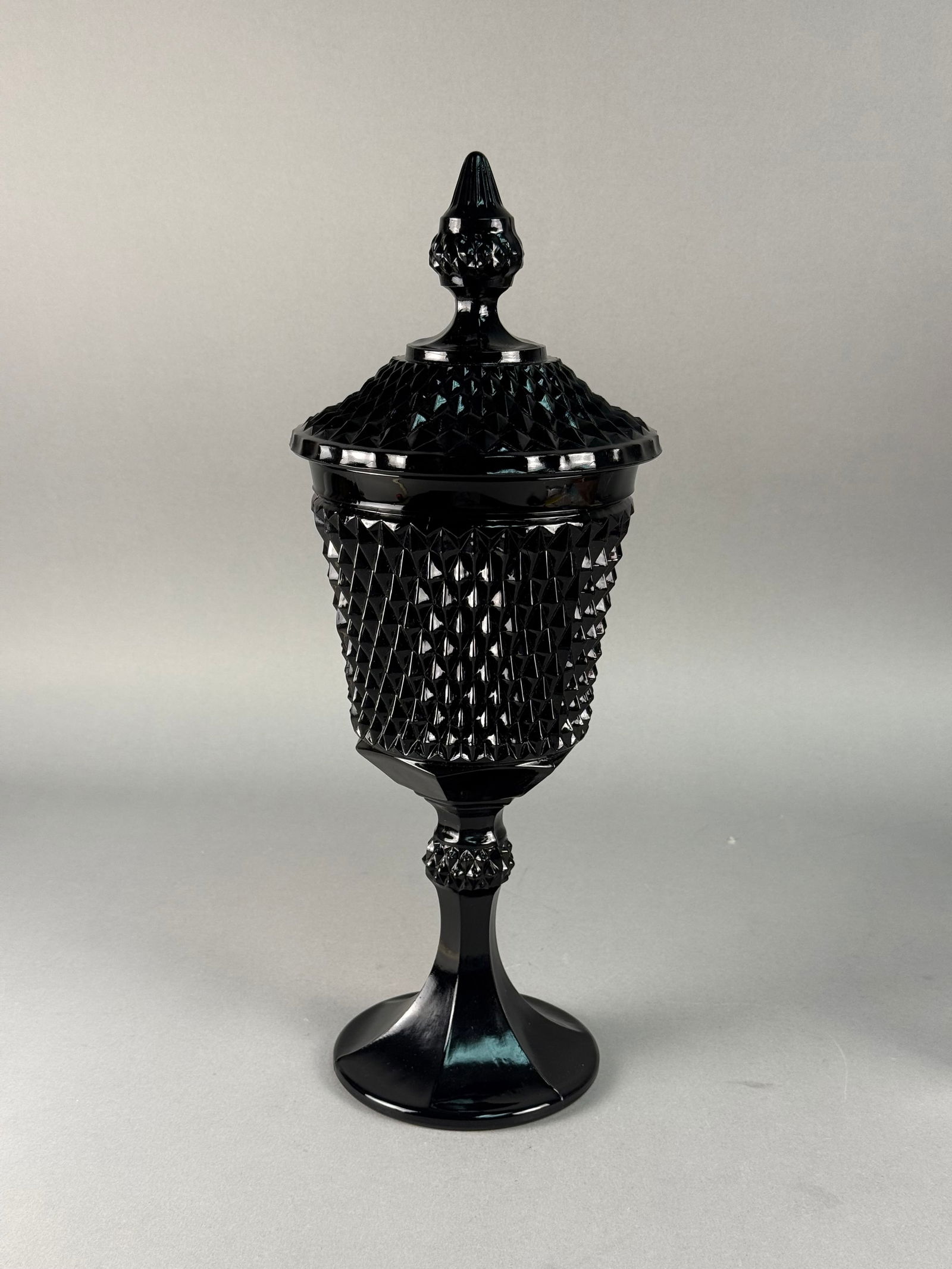 Tiara Exclusive Pressed Black Glass Diamond Point Covered Urn: A large pressed glass covered urn or compote produced for Tiara Exclusive, manufactured by the Indiana Glass Company. The piece is rendered in opaque black glass and features the Diamond Point pattern