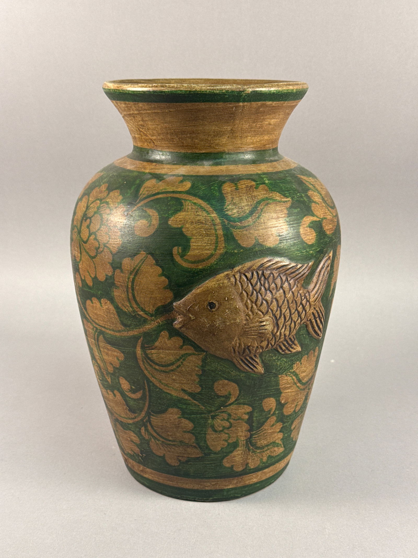 Thai Carved Decorative Vase with Relief Fish and Foliate Scrolls: A decorative Thai vase of tapered form, likely composed of carved wood or a molded composite material. The vessel features a vibrant green ground accented by hand-painted ocher foliate and floral scro