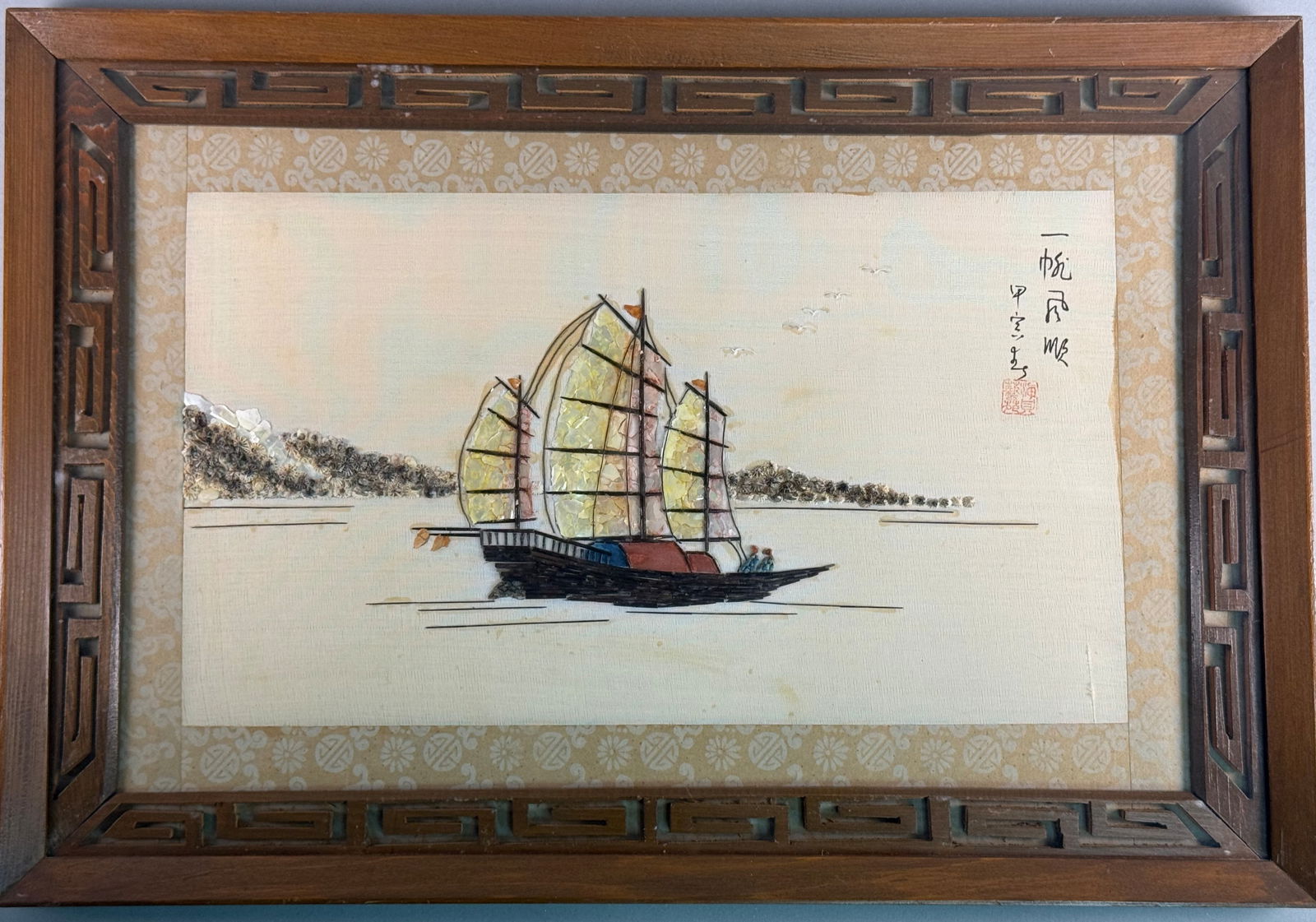 Chinese Mixed-Media Shell Art Depicting a Junk Ship: Chinese mixed-media artwork depicting a traditional three-masted junk ship on calm waters. The composition is constructed using iridescent shell fragments for the sails and applied wood for the hull.