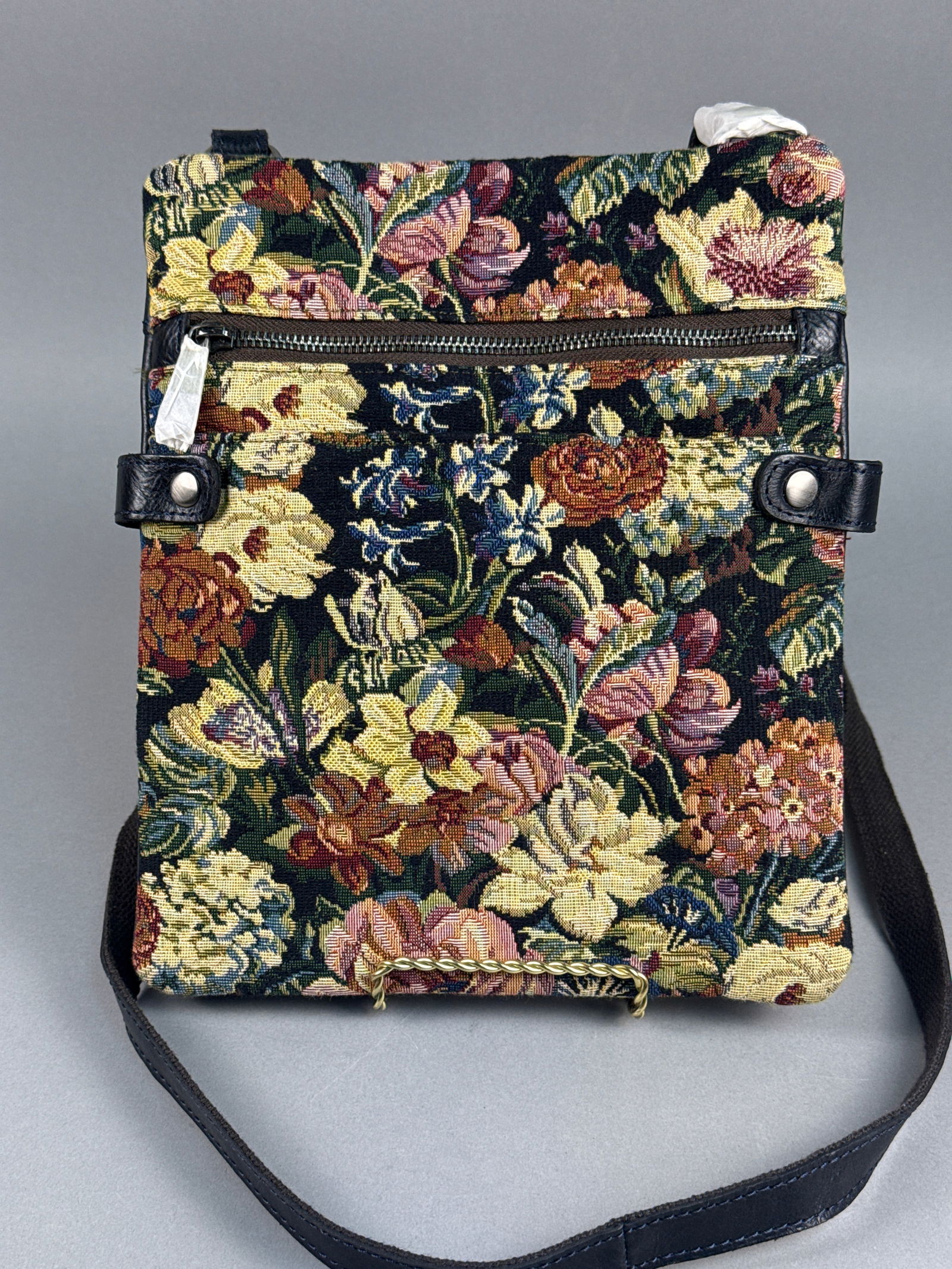 Patricia Nash Woven Floral Tapestry and Leather Crossbody Bag: This Patricia Nash crossbody bag is from the Woven Floral Tapestry Collection. The design features a front panel of multi-color floral tapestry and a back panel of black pebbled leather with an emboss