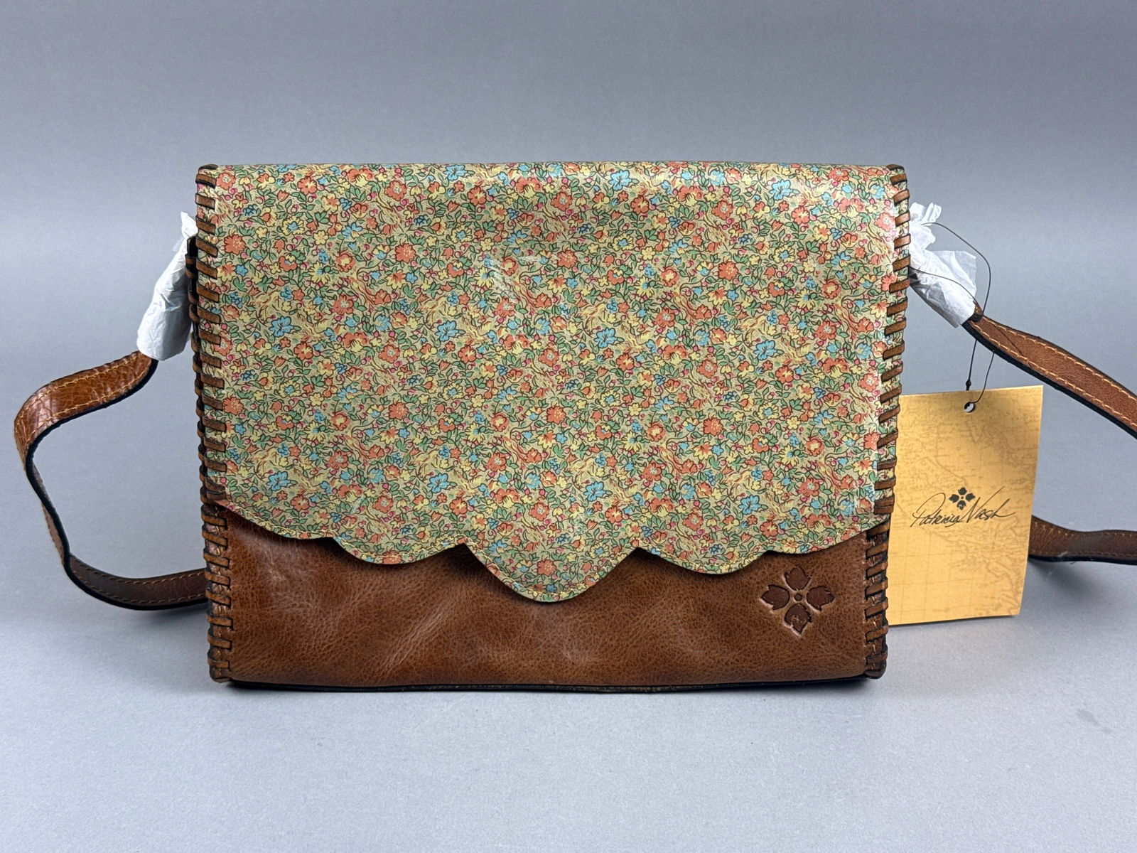 Patricia Nash Lanza Leather Crossbody Bag, Tan with Floral Scalloped Flap: This Patricia Nash crossbody bag, identified as the Lanza style, showcases the brandâ€™s signature vintage-inspired aesthetic. The body is crafted from rich, distressed cognac tan full-grain l