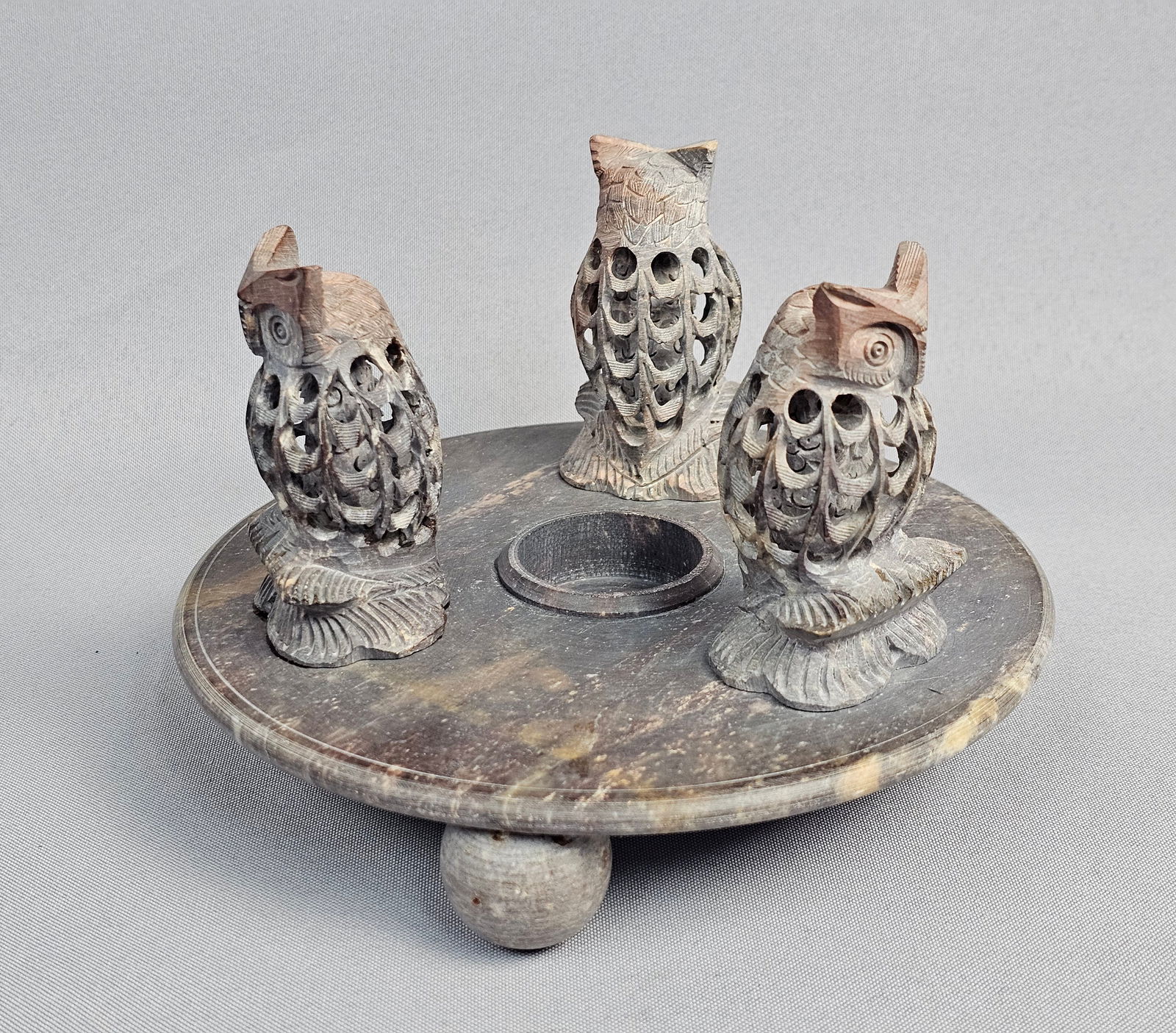 A Hand Carved Undercut Soapstone Owl Candle Holder Stand: A hand-carved soapstone decorative stand or candle holder featuring traditional Indian jali craftsmanship. The piece is constructed from a circular platform supported by three spherical feet and inclu