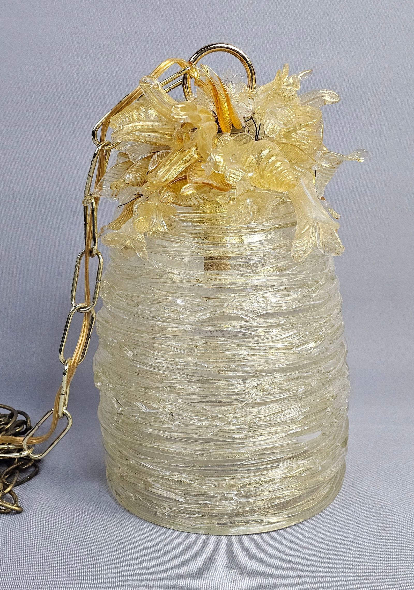 Vintage Murano Style Textured Glass Pendant Hanging Light: A mid-century modern pendant light fixture. The fixture features a cylindrical glass shade with a spun-glass thread texture. The upper section is embellished with a cluster of handmade glass flowers a