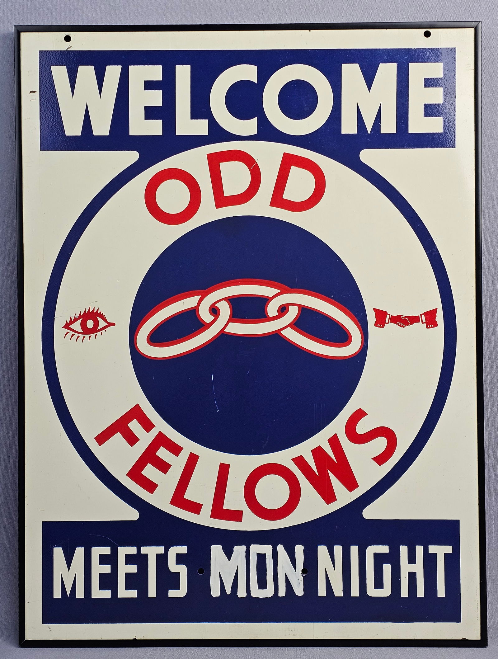 Independent Order of Odd Fellows (IOOF) Enamel Sign, Welcome Meets Monday Night: The sign utilizes a traditional red, white, and blue color scheme and displays the primary symbols of the organization: the three-link chain representing Friendship, Love, and Truth, the All-Seeing Ey