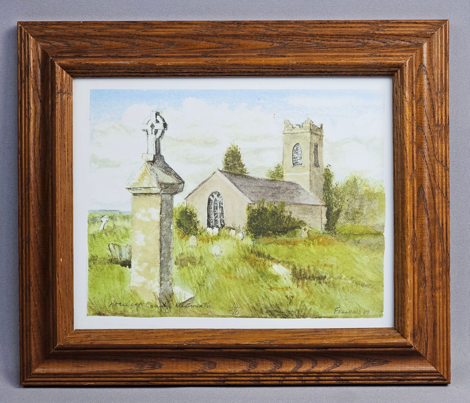 Dave Fellows Signed Horseleap County Westmeath Print 10/10: Dave Fellows watercolor print. This representational landscape depicts an Irish church and its graveyard in Horseleap, County Westmeath. The composition features a prominent Celtic cross monument in