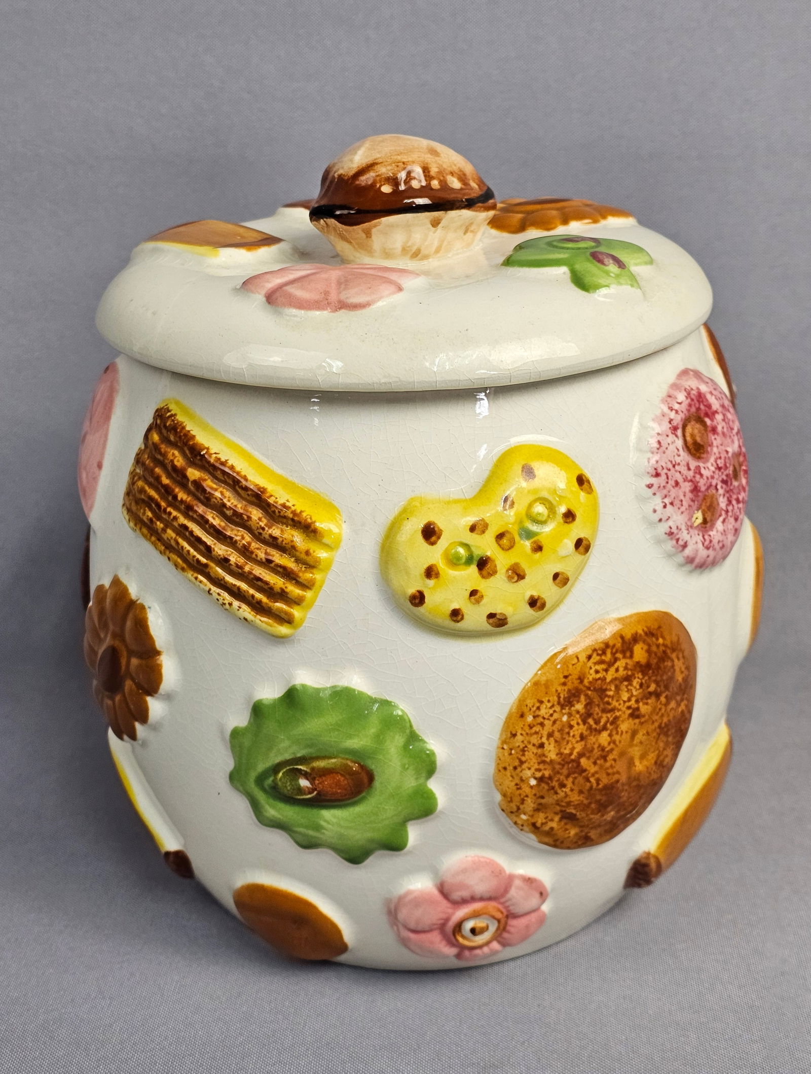 Vintage Napco Cookies All Over Ceramic Cookie Jar, Mid-Century Modern: A vintage ceramic cookie jar and matching lid produced by the National Potteries Company (NAPCO). This piece features the popular Cookies All Over pattern, characterized by multi-colored molded relief