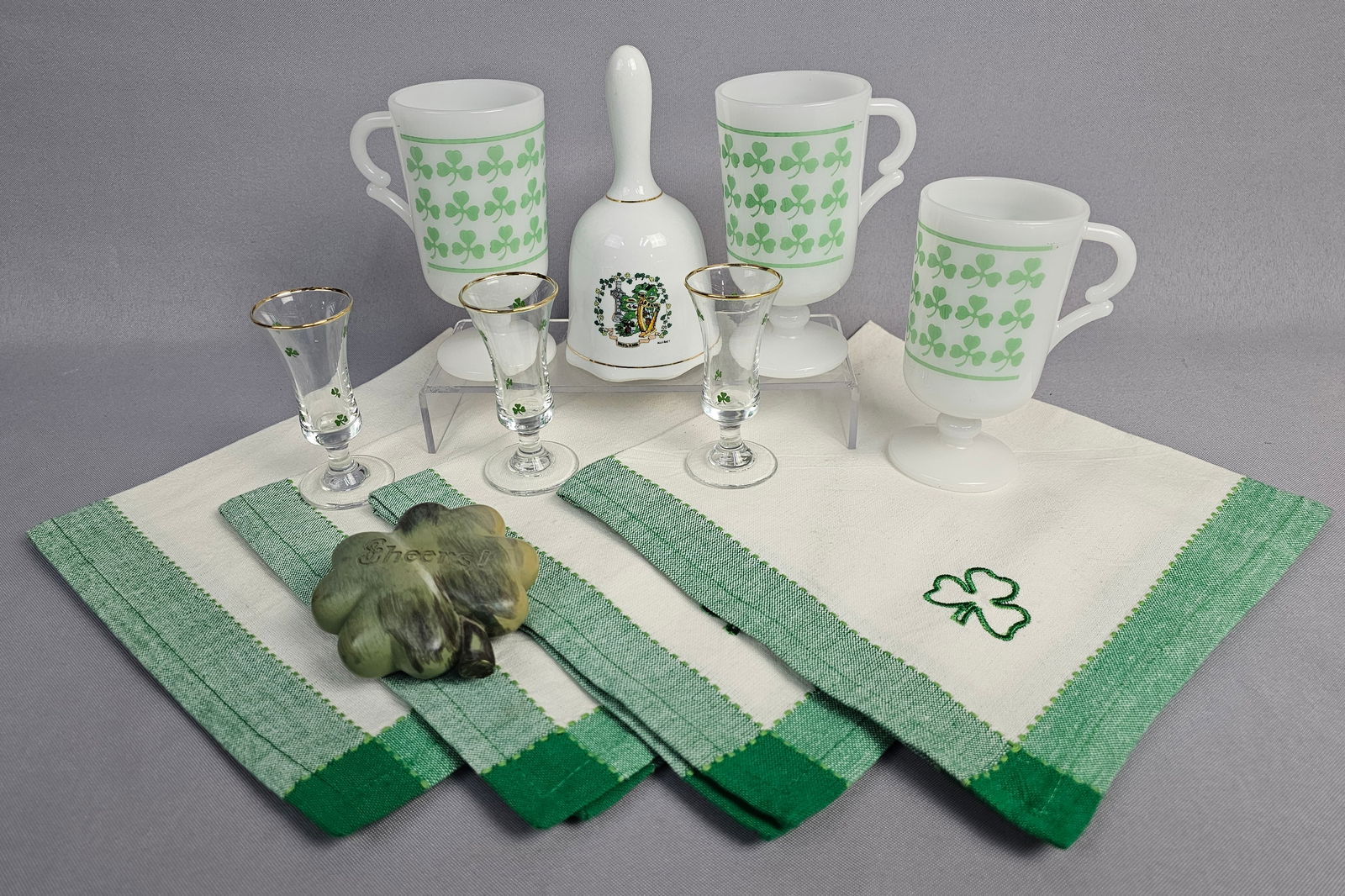 Vintage Irish-Themed Tableware and Souvenir Collection - 12 Pieces: A diverse collection of Irish-themed decorative and tablewares. The set includes three vintage milk glass pedestal Irish coffee mugs featuring a printed green shamrock band, characteristic of mid-cent