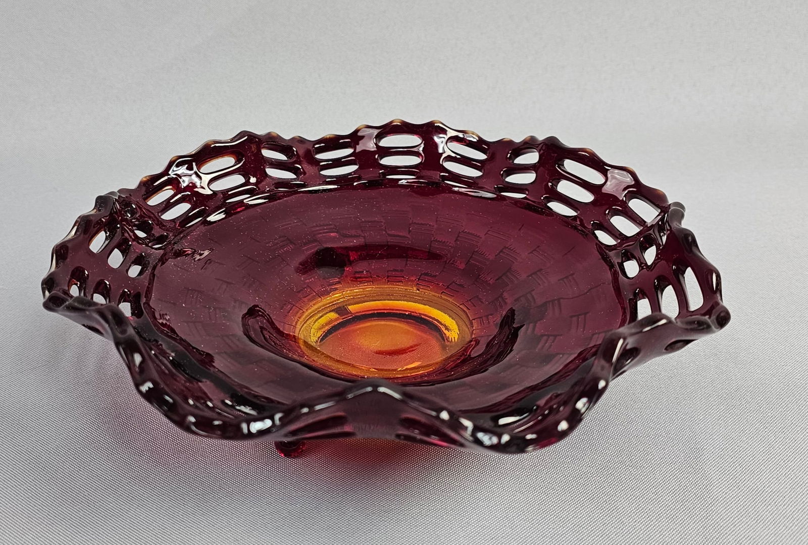 Fenton Art Glass, Amberina Pressed Glass Basket Weave Tri-Footed Bowl: This vibrant mid-century bowl is a classic production of the Fenton Art Glass Company, identified as the #1092 pattern. The piece is executed in Amberina glass, a decorative style achieved by adding