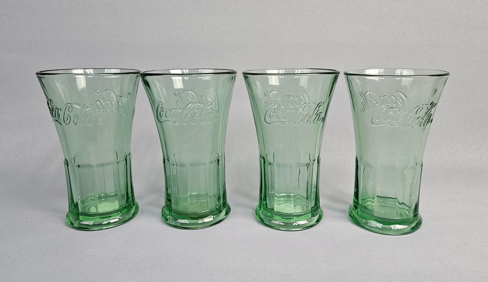 Set of 4 Libbey Coca-Cola Flared Tumblers: A set of four licensed Coca-Cola drinking glasses manufactured by the Libbey Glass Company. Height: 6 inches. The set is in excellent condition. There are no chips, cracks, or visible signs of wear