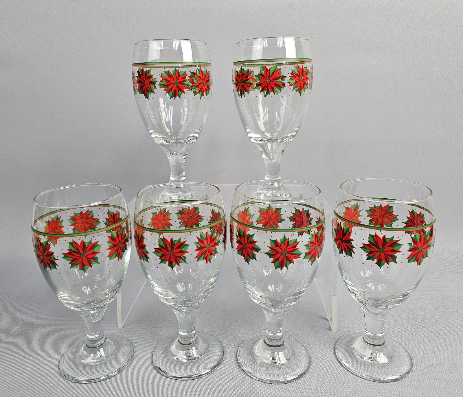Libbey Set of Six Vintage Painted Poinsettia Glass Goblets: A set of six clear glass stemmed goblets featuring a festive seasonal motif. Each vessel is decorated with a repeating enamel-painted band of red poinsettias with green leaves, further accented by sca