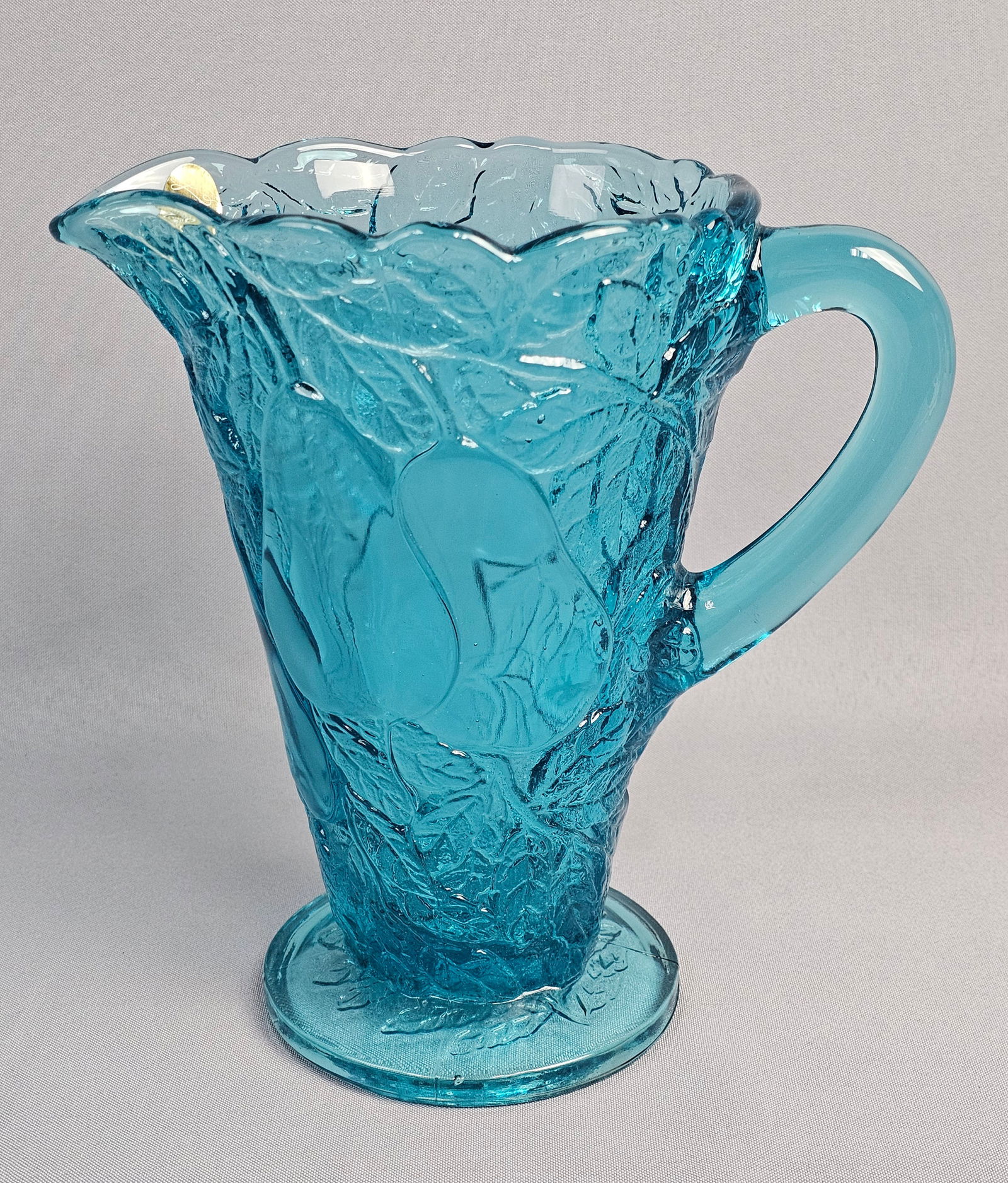 Tiara Exclusives Pears Pattern Aqua Pressed Glass Pitcher: This vintage footed pitcher was distributed by Tiara Exclusives and manufactured by the Indiana Glass Company. It is executed in a vibrant aqua blue pressed glass, featuring the Pears pattern, which i