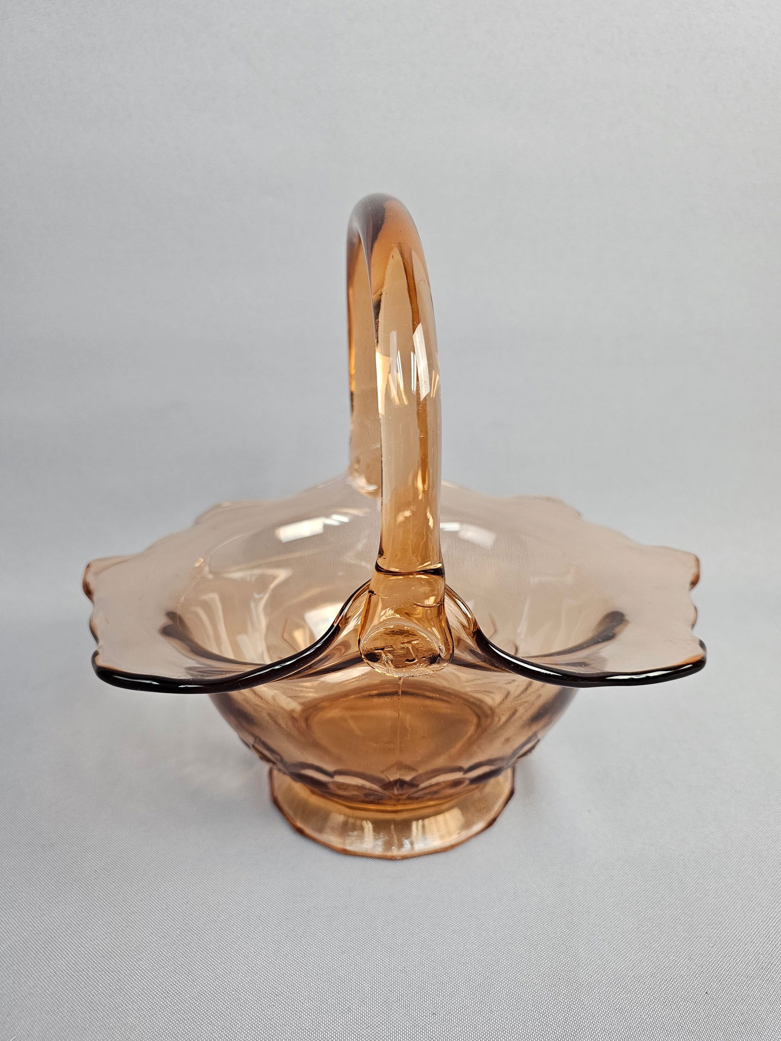 Depression Era Mold-Pressed Glass Basket in Topaz: A Depression-era pressed glass basket featuring a translucent peach or light amber hue, often identified as Topaz in period catalogs. The piece consists of a mold-pressed bowl with a flared, scalloped