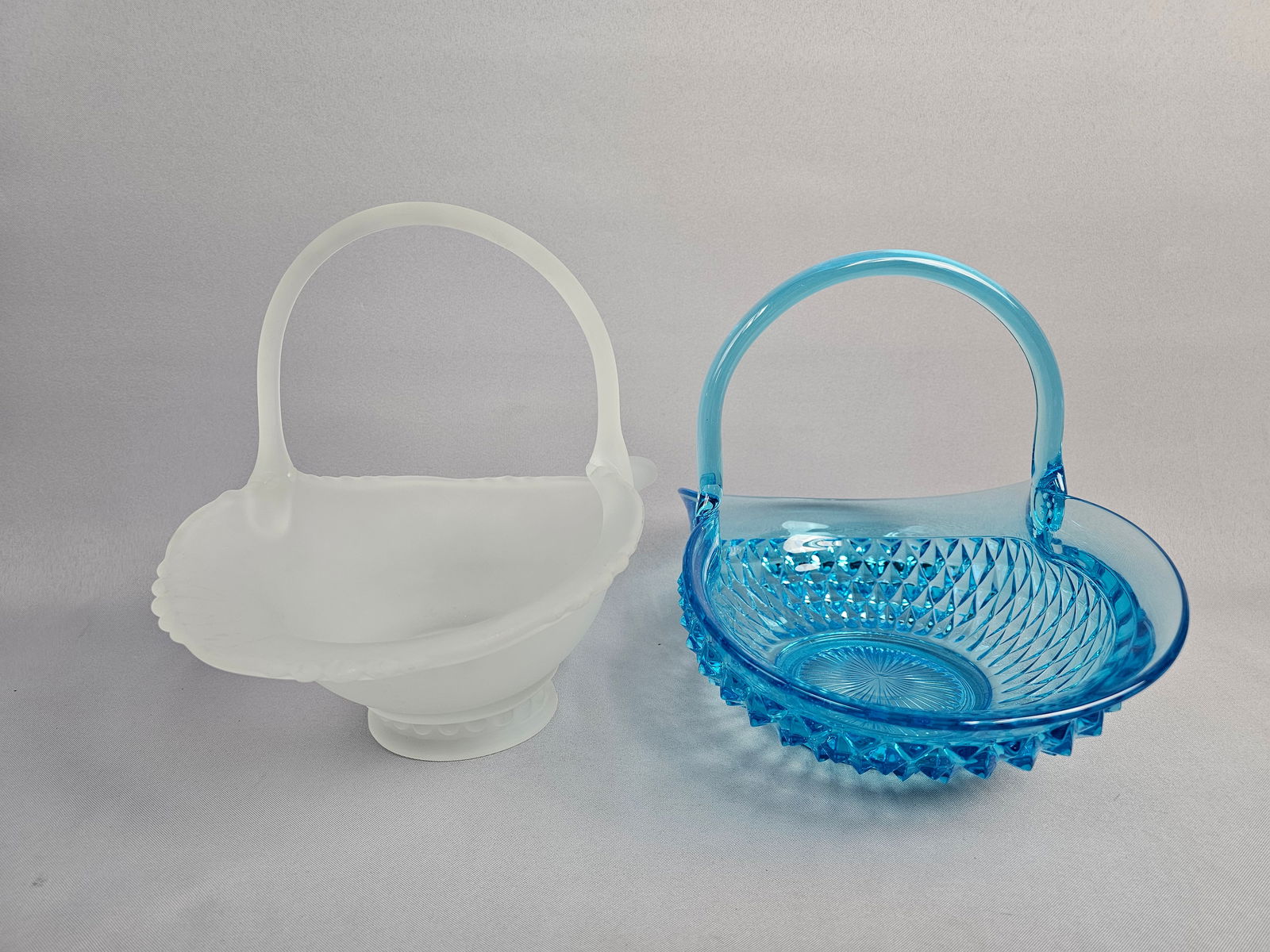A Pair of Vintage American Art Glass Baskets: This lot features two distinct examples of mid-century American art glass. The first is a vibrant Capri Blue pressed glass basket manufactured by the Imperial Glass Corporation of Ohio. This piece fea